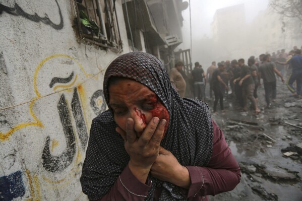 A wounded Palestinian woman runs away following Israeli airstrikes that targeted her neighborhood in Gaza City on Monday, Oct. 23, 2023. (AP Photo/Abed Khaled)