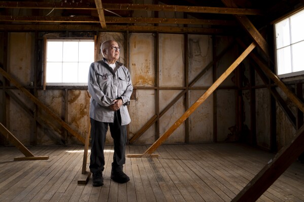 Paul Tomita poses for a portrait in a historic barracks at Minidoka National Historic Site, Saturday, July 8, 2023, in Jerome, Idaho. Tomita, who had asthma as an infant, says the constant desert dust that seeped even into the barracks repeatedly sent him to the camp hospital. "Dust on your face, dust in your ears, dust up your nose, dust in your mouth," he remembers. (APPhoto/Lindsey Wasson)