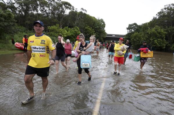 People wade through flood water as they relocate in Chinderah, Australia, Tuesday, March 1, 2022. Tens of thousands of people had been ordered to evacuate their homes and many more had been told to prepare to flee as parts of Australia's southeast coast are inundated by the worst flooding in decades. (Jason O'Brien/AAP Image via AP)