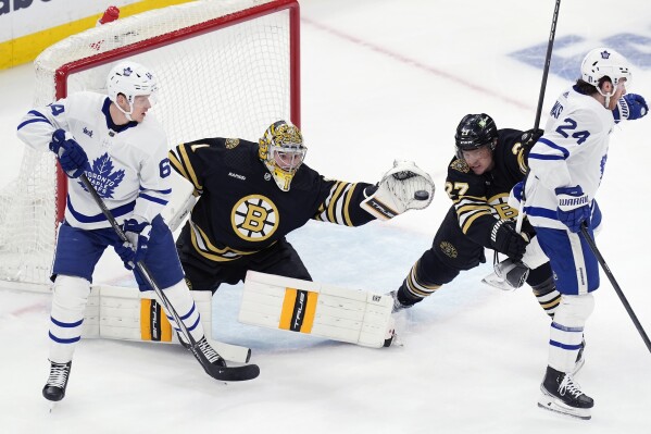 Boston Bruins' Jeremy Swayman (1) makes a glove save behind Toronto Maple Leafs' David Kampf (64) as Hampus Lindholm (27) defends against Toronto Maple Leafs' Connor Dewar (24) during the first period of Game 7 of an NHL hockey Stanley Cup first-round playoff series, Saturday, May 4, 2024, in Boston. (AP Photo/Michael Dwyer)