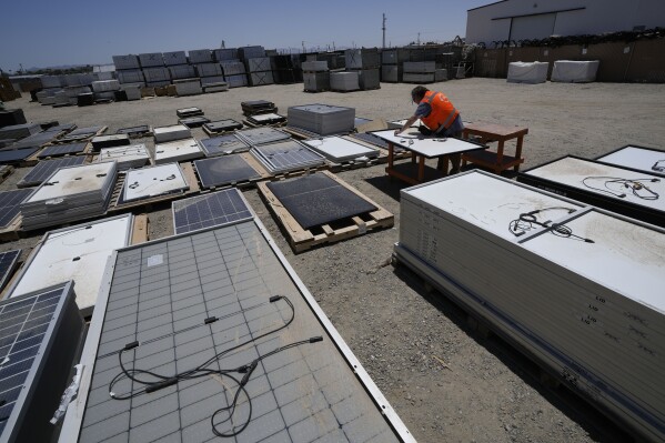Dwight Clark inspects a used solar panel at We Recycle Solar on Tuesday, June 6, 2023, in Yuma, Ariz. (AP Photo/Gregory Bull)