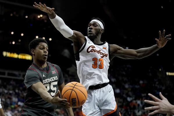 Oklahoma guard Grant Sherfield (25) passes around Oklahoma State forward Moussa Cisse (33) during the first half of an NCAA college basketball game in the first round of the Big 12 Conference tournament Wednesday, March 8, 2023, in Kansas City, Mo. (AP Photo/Charlie Riedel)