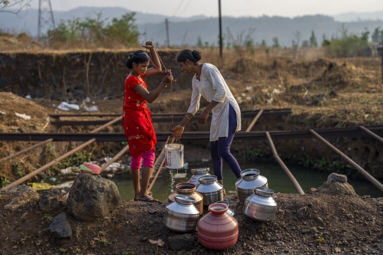 Women draw water for cleaning and washing from a pit in an open field near Shahapur, northeast of Mumbai, India, Saturday, May 6, 2023. (AP Photo/Dar Yasin)