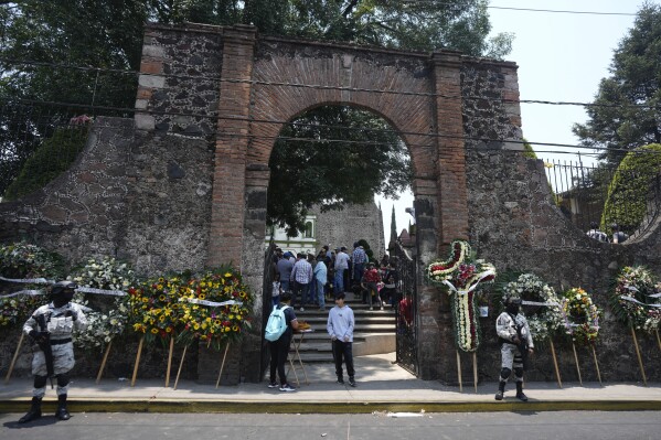 Mexican National Guard officers stand guard outside the church holding the funeral service for four men slain in a mass shooting, in Huitzilac, Mexico, Tuesday, May 14, 2024. The shooting in the mountain township beset by crime just south of Mexico City resulted in several deaths, authorities said Sunday. (AP Photo/Fernando Llano)