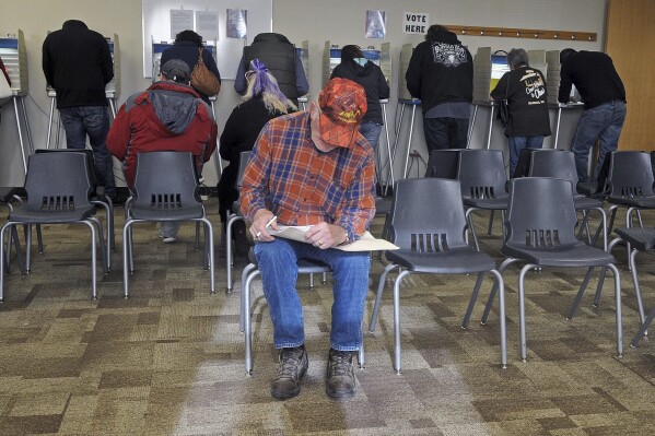 FILE - With all the voting booths filled with people, Ronald Moffit sits down to complete his ballot inside Lincoln City Hall, Nov. 8, 2016, in Lincoln, N.D. North Dakota would become the first state to require hand-counting of all election ballots if voters back a proposed ballot measure that would achieve a goal of activists across the country who distrust modern vote counting. (Tom Stromme/The Bismarck Tribune via AP, File)