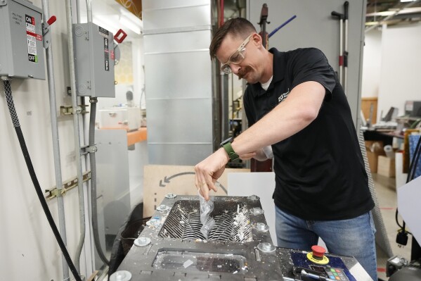 Tyler Eglen, project manager Walton Sustainability Solutions Service, shreds a cup at the Arizona State University Circular Living Lab Wednesday, June 7, 2023, in Mesa, Ariz. Cups, part of the "borrowed" cup program too damaged to be reused, along with disposable Starbucks cold drink cups and other plastic found in the trash, are sent to the lab. They're shredded, melted and extruded into long, lumber-like pieces. (AP Photo/Ross D. Franklin)