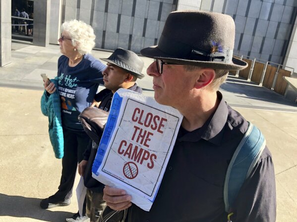 Ben Terrall holds a protest sign that reads "Close The Camps" outside of the San Francisco Federal Courthouse on Wednesday, July 24, 2019 in San Francisco, Calif. A federal judge said Wednesday that the Trump administration can enforce its new restrictions on asylum for people crossing the U.S.-Mexico border while lawsuits challenging the policy play out. (AP Photo/Haven Daley)