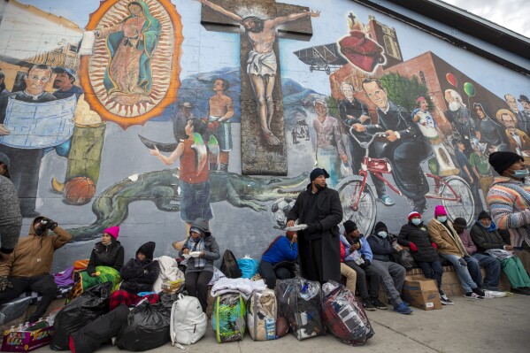 FILE - Migrants eat and wait for assistance while camping on a street in downtown El Paso, Texas, Sunday, Dec. 18, 2022. Christian voters and faith leaders have long been in the frontlines of providing assistance to migrants – but when it comes to support for immigration policies, from border security to legalization options for migrants already in the U.S., views diverge broadly. (AP Photo/Andres Leighton, File)