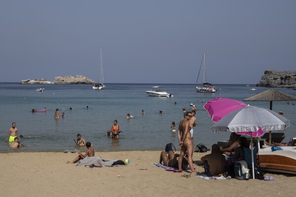 Tourists enjoy the beach and the sea in Lindos, on the Aegean Sea island of Rhodes, southeastern Greece, on Thursday, July 27, 2023. (AP Photo/Petros Giannakouris, File)