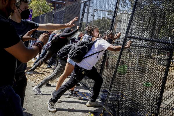 Protesters attempt to push down a gate surrounding People's Park in Berkeley, Calif. on Wednesday, Aug. 3, 2022. Protesters gathered to decry the clearing out of the park in preparation for the development of student housing. (Brontë Wittpenn/San Francisco Chronicle via AP)