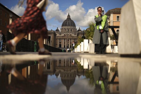 People walk near the St. Peter's Basilica, background, in Rome, on Tuesday, May 6, 2025, the day before of the upcoming conclave starting on May 7, to elect the 267th Roman pontiff. (AP Photo/Francisco Seco)