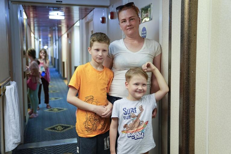 Marina Nosylenko stands with her two sons on the ferry Isabelle in Tallinn, Estonia, Wednesday, June 15, 2022. Nosylenko left Mariupol on May 26 and took the train to St. Petersburg, Russia, with her husband and three children. They left Russia as quickly as possible, making the entire journey to Estonia in three days. (AP Photo)