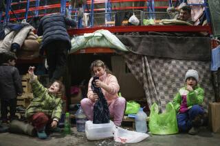 A woman washes clothes as migrants settle at the "Bruzgi" checkpoint logistics center at the Belarus-Poland border near Grodno, Belarus, Thursday, Dec. 23, 2021. Since Nov. 8, a large group of migrants, mostly Iraqi Kurds, has been stranded at a border crossing with Poland. Most of them are fleeing conflict or hopelessness at home, and aim to reach Western European countries. But as temperatures fall below freezing, life at the border becomes more challenging. (AP Photo/Pavel Golovkin)