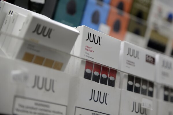 FILE - In this Dec. 20, 2018, file photo Juul products are displayed at a smoke shop in New York.  The Federal Trade Commission on Wednesday, April 1, 2020, sued to break up the multibillion-dollar partnership between tobacco giant Altria and e-cigarette startup Juul Labs. In a legal filing Wednesday, the watchdog agency said the financial and business dealings between the companies amounted to an agreement not to compete.(AP Photo/Seth Wenig, File)