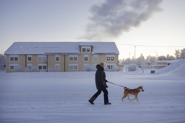 A person walks a dog in the village of Vittangi in Kiruna municipality, north Sweden, Wednesday, Jan. 3, 2024 (Emma-Sofia Olsson/TT News Agency via AP)
