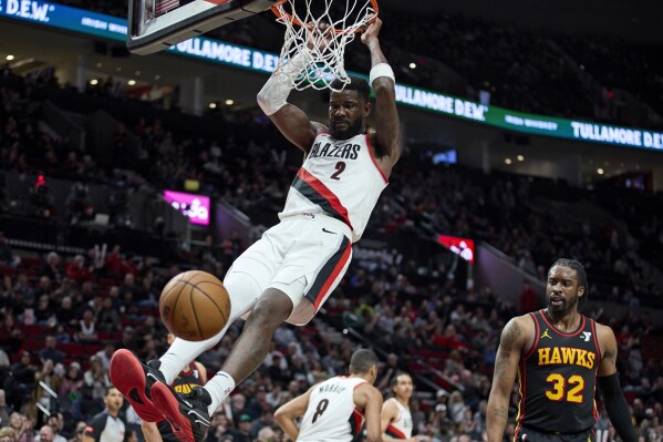 Portland Trail Blazers center Deandre Ayton, left, dunks in front of Atlanta Hawks guard Wesley Matthews during the second half of an NBA basketball game in Portland, Ore., Wednesday, March 13, 2024. (AP Photo/Craig Mitchelldyer)