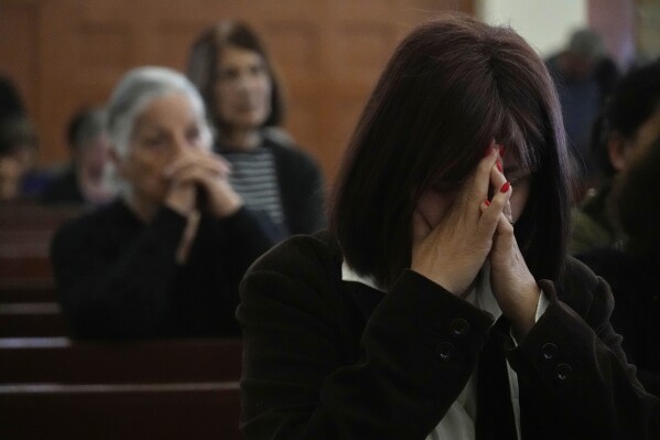 Maronite Catholic faithful bring their hands together in prayer during a service in outside St. George Church in the Maronite village of Kormakitis in the breakaway north of the ethnically divided Cyprus on Wednesday, April 23, 2025. (AP Photo/Petros Karadjias)