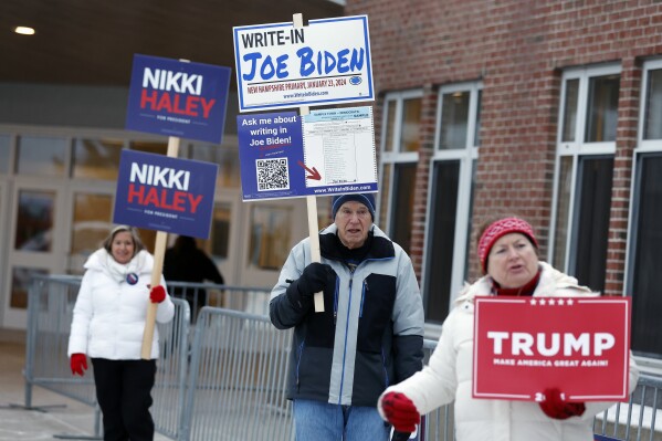 FILE - Candidate supporters stand outside a polling location in the presidential primary election, Jan. 23, 2024, in Windham, N.H. Super Tuesday is feeling anything but for many Americans, with the leading presidential contenders already appearing set. A primary season that engages only a fraction of the electorate to choose the presidential candidates is a reminder of how the U.S. election system excludes many voters and differs starkly from that of most other democracies around the world. (AP Photo/Michael Dwyer, File)