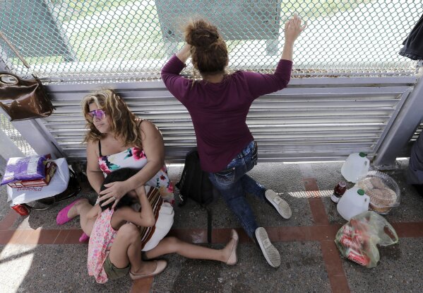 
              CORRECTS YEAR OF PHOTO TO 2018, NOT 2019 - FILE - In this June 24, 2018, file photo, immigrants from Honduras seeking asylum wait on the Gateway International Bridge, which connects the United States and Mexico, in Matamoros, Mexico. The Trump administration wants up to two years to find potentially thousands of children who were separated from their parents at the border before a judge halted the practice. The Justice Department said in a court filing late Friday, April 5, 2019, in San Diego that it will take at least a year to review the cases of 47,000 unaccompanied children taken in custody between July 1, 2017 and June 25, 2018. (AP Photo/David J. Phillip, File)
            