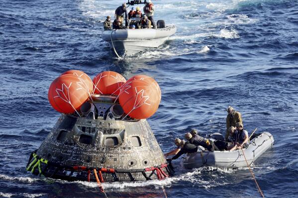 U.S. Navy divers secure NASA's Orion capsule during recovery operations after it splashed down in the Pacific off Mexico, Sunday, Dec. 11, 2022, concluding a 25-day test flight. The mission should clear the way for astronauts on the program’s next lunar flyby, set for 2024. (Mario Tama/Pool Photo via AP)