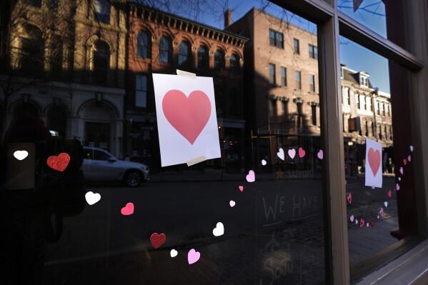 Valentine's Day Hearts decorate a storefront on Exchange Street, Wednesday, Feb. 14, 2024, in Portland, Maine. The public has helped honor the memory of Kevin Fahrman, the Valentine's Day Bandit who secretly hung hundreds of red paper hearts throughout the city every February 14th. Farman died last year. (AP Photo/Robert F. Bukaty)