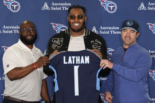 Tennessee Titans first round draft pick JC Latham, center, poses with general manager Ran Carthon, left, and head coach Brian Callahan, right, at an NFL football news conference Friday, April 26, 2024, in Nashville, Tenn. (AP Photo/George Walker IV)