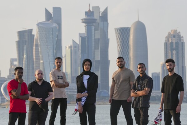 From left, Said Fadel, Samir al Borno, Abood Qassim, Rahaf Shamaly, Ahmed Haddad, Fares Anbar and Hamada Nasrallah of the Gaza Strip-based Sol Band pose for a photograph in Doha, Qatar, Thursday, May 2, 2024. (AP Photo/Lujain Jo)