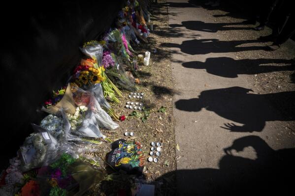 FILE - Visitors cast shadows at a memorial to the victims of the Astroworld concert in Houston on Nov. 7, 2021. The 10 people who lost their lives in a massive crowd surge at the Astroworld music festival in Houston died from compression asphyxia, officials announced Thursday, Dec. 16, 2021. (AP Photo/Robert Bumsted, File)