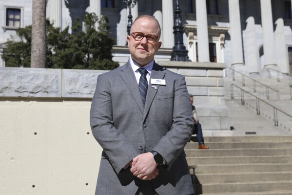 Chase Glenn, executive director of Alliance for Full Acceptance, stands outside the South Carolina Statehouse before a rally against a bill banning gender-affirming care for minors, Wednesday, Feb. 14, 2024, in Columbia, S.C. LGBTQ+ advocates like Glenn say that Republican presidential candidates' rhetoric around transgender-related issues is jeopardizing the safety of an already vulnerable community. (AP Photo/Jeffrey Collins)