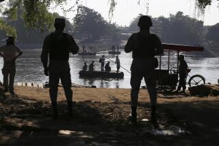 FILE - Mexican National Guards stand watch over the Suchiate River where locals transport cargo and ferry people between Mexico and Guatemala, near Ciudad Hidalgo, Mexico, Friday, Jan. 24, 2020, a location popular for Central American migrants to cross from Guatemala to Mexico. Mexican migration policy is increasingly militarized. (AP Photo/Marco Ugarte, File)