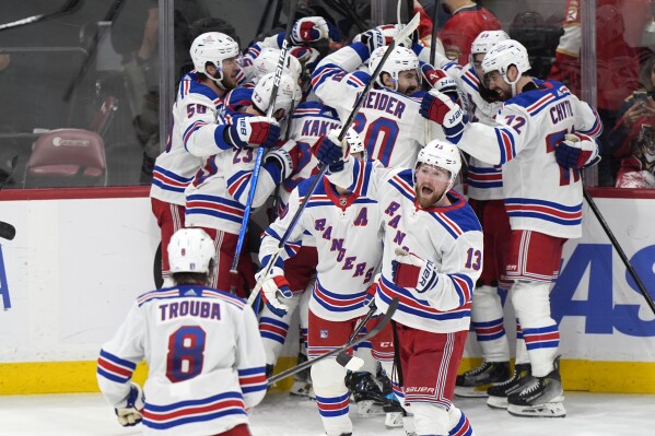 New York Rangers players celebrate after the beat the Florida Panthers 5-4, in an overtime period of Game 3 during the Eastern Conference finals of the NHL hockey Stanley Cup playoffs, Sunday, May 26, 2024, in Sunrise, Fla. (AP Photo/Wilfredo Lee)