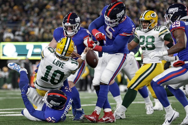 Green Bay Packers quarterback Jordan Love (10) fumbles the ball as he is tackled by New York Giants safety Jason Pinnock (27) and linebacker Kayvon Thibodeaux (5) during the second quarter of an NFL football game, Monday, Dec. 11, 2023, in East Rutherford, N.J. (AP Photo/Adam Hunger)