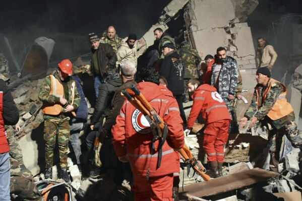 In this photo released by the Syrian official news agency SANA, Syrian security forces and civil defence workers search for victims under the rubbles of a building that was destroyed by Israeli airstrikes, in Homs, Syria, late Tuesday, Feb. 6, 2024. Syria's military says Israeli airstrikes over the central city of Homs and nearby areas have killed and wounded civilians. (SANA via AP)