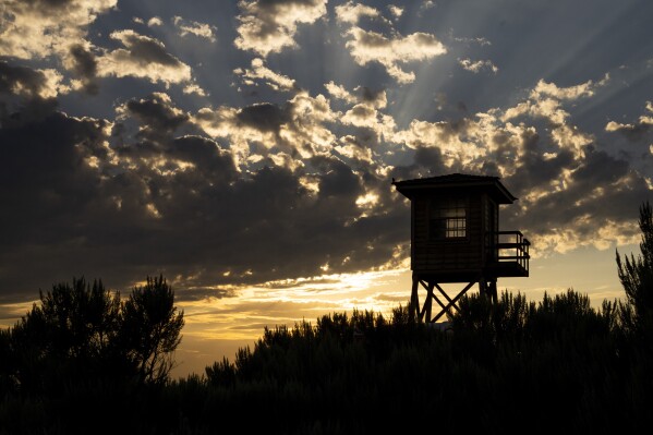 A reconstructed entry guard tower is silhouetted by the sunset at Minidoka National Historic Site, Saturday, July 8, 2023, in Jerome, Idaho. The original guard tower was one of eight such structures manned by United States military on the site surrounded by miles of barbed wire. (AP Photo/Lindsey Wasson)