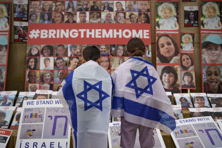 FILE - Children look at photographs of Israelis kidnapped by Hamas during a rally joined by hundreds in solidarity with Israel and those held hostage in Gaza, in Bucharest, Romania on Nov. 2, 2023. (AP Photo/Vadim Ghirda)