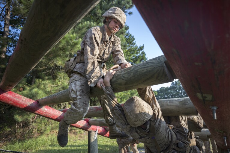 A female U.S. Marine Corps recruit, left, helps a fellow recruit while training on an obstacle in the Crucible at the Marine Corps Recruit Depot, Thursday, June 29, 2023, in Parris Island, S.C. (AP Photo/Stephen B. Morton)