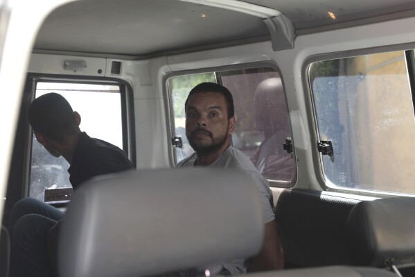 Unidentified Colombian suspects sit in a van in handcuffs as they arrive to appear before the investigating judge appointed to the case of the assassination of Haitian President Jovenel Moise in Port-au-Prince, Haiti, Tuesday, Aug. 29, 2023. Moise was assassinated on July 7, 2021, when he was shot a dozen times at his private home in an attack that also seriously injured his wife. (AP Photo/Odelyn Joseph)