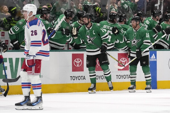 New York Rangers' Jimmy Vesey (26) skates to the bench as Dallas Stars' Jamie Benn (14) and Joe Pavelski (16) celebrate with the bench after Benn scored in the second period of an NHL hockey game in Dallas, Monday, Nov. 20, 2023. (AP Photo/Tony Gutierrez)