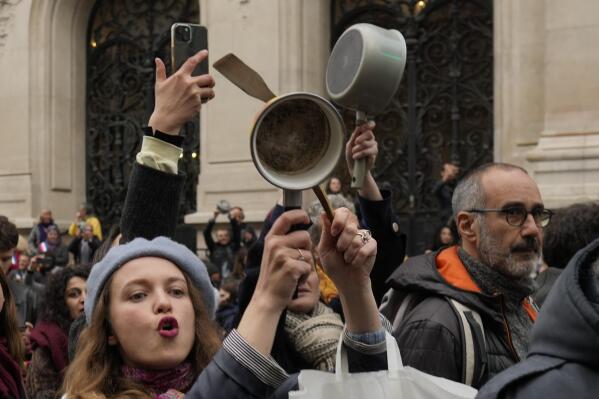 FILE - People bang pots and pans while French President Emmanuel Macron speaks in a televised address to the nation, Monday, April 17, 2023 in Paris. A country renowned for its cuisine is turning to pots and pans to express discontent with French President Emmanuel Macron's pension reforms. French demonstrations against raising the retirement age from 62 to 64 have morphed from lobbing paving stones, dodging tear gas and brandishing banners to something nearer the soul of the gastronomic nation: Making noise by banging kitchen saucepans. (AP Photo/Thibault Camus, File)