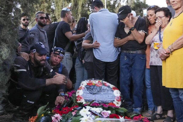 Mourners gather around the grave of Chen Amir during his funeral in Kibbutz Re'im, Israel, Sunday, Aug 6, 2023. On Saturday a Palestinian gunman shot and killed Amir, 42, an Israeli security guard in central Tel Aviv. The attacker was shot and killed. (AP Photo/Tsafrir Abayov)