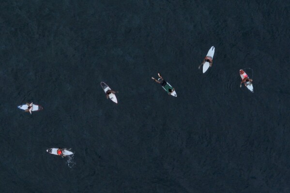 Surfers wait to catch the perfect wave in Teahupo'o, Tahiti, French Polynesia, Saturday, Jan. 13, 2024. (AP Photo/Daniel Cole)