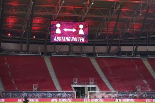 "Keep your distance" is written on the scoreboard above the empty stands during the German Bundesliga soccer match between RB Leipzig and Bayer Leverkusen, at the Red Bull Arena in Leipzig, Germany, Sunday, Nov. 28, 2021. (Jan Woitas/dpa via AP)