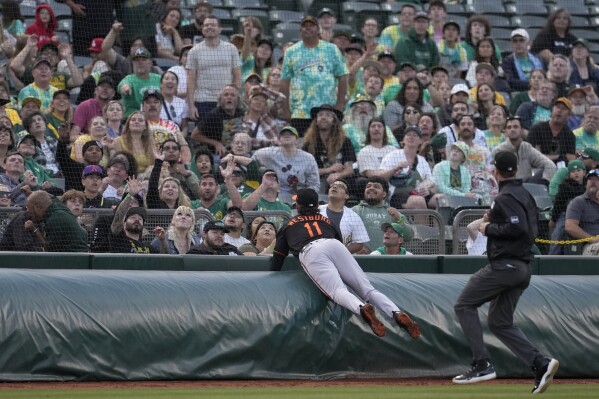 Fans watch as Baltimore Orioles third baseman Jordan Westburg (11) goes after a foul ball, which he did not catch, hit by Oakland Athletics' Seth Brown during the third inning of a baseball game in Oakland, Calif., Friday, Aug. 18, 2023. (AP Photo/Jeff Chiu)