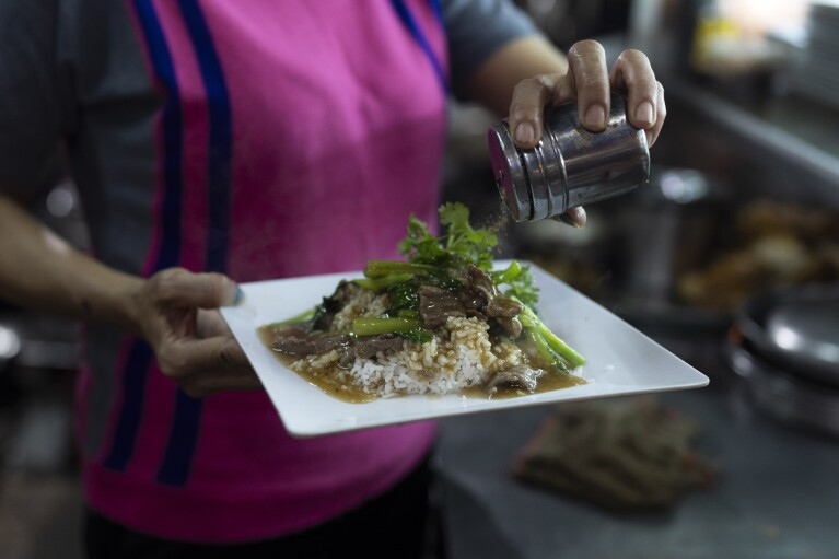 2024 年 1 月 24 日星期三，越南胡志明市，一名餐厅工作人员在米饭上撒上碎胡椒。米饭不仅是大多数膳食的主食，还被认为是来自神的礼物，并继续受到人们的崇拜。  （美联社照片/Jae C. Hong）