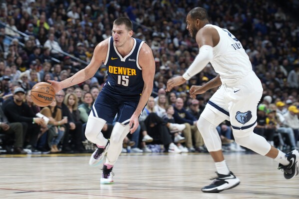 Denver Nuggets center Nikola Jokic, left, drives past Memphis Grizzlies forward Xavier Tillman, right, in the first half of an NBA basketball game Thursday, Dec. 28, 2023, in Denver. (AP Photo/David Zalubowski)