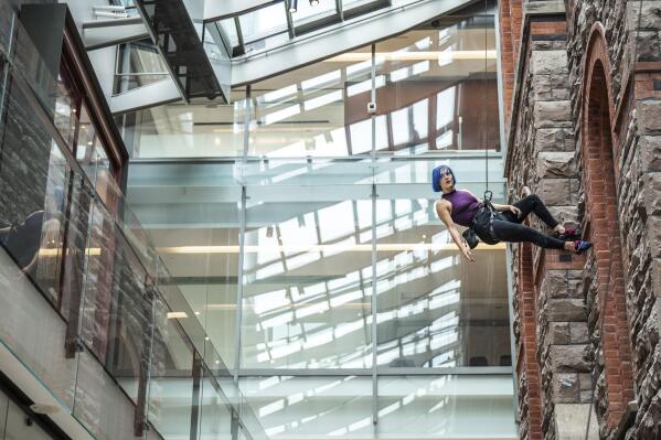 This image provided by Tapestry Opera shows Lauren Pearl climbing a wall as she performs the role of Louise in "Gould's Wall." (Dahlia Katz/Tapestry Opera via AP)