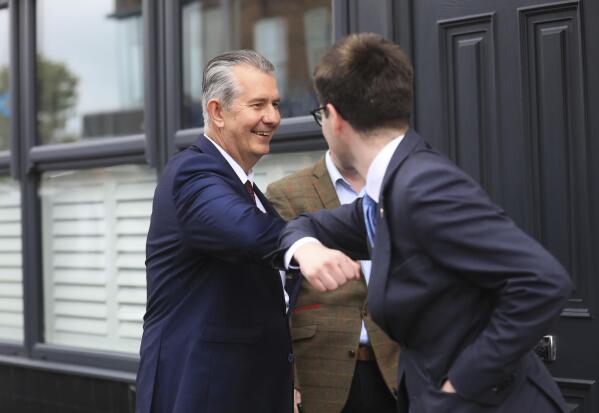Democratic Unionist Party members Edwin Poots, left, is greeted by a supporter on the Belmont road after leaving the party headquarters in east Belfast after voting took place to elect a new leader on Friday May 14, 2021. Edwin Poots and Jeffrey Donaldson are running to replace Arlene Foster. (AP Photo/Peter Morrison)
