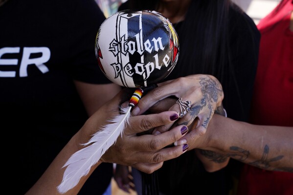 Grassroots advocates hold a Native American gourd rattle at Drumbeat Indian Arts, Monday, July 31, 2023, in Phoenix. The women are trying to help find lost Native Americans who were left without a place to stay after the phony treatment centers in the Phoenix area abruptly shut down when Arizona cut off their Medicaid money amid investigations into widespread fraudulent billing. (AP Photo/Ross D. Franklin)