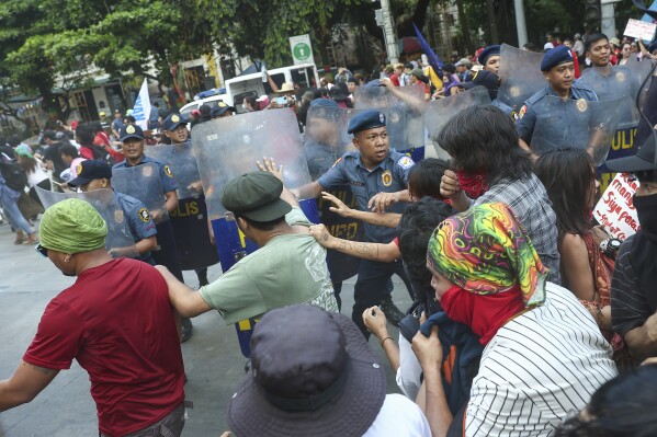 Policemen try to block activists as they tried to march towards the U.S. Embassy during a protest to mark International Labor Day in Manila, Philippines on Wednesday, May 1, 2024. Hundreds of Filipino workers from various labor groups took to the streets to mark Labor Day and demand a wage increase and job security amid soaring food and oil prices. (AP Photo/Basilio Sepe)