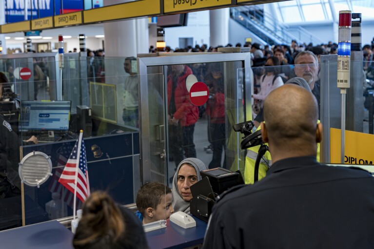 Four-year-old Omar Abu Kuwaik, center, and his aunt Maha Abu Kuwaik, both from Gaza, are processed by a US Customs and Border Protection agent at John F. Kennedy International Airport, Wednesday, Jan. 17, 2024, in New York. Through the efforts of family and strangers, Omar was brought out of Gaza and to the United States, where he received treatment, including a prosthetic arm. (AP Photo/Peter K. Afriyie)